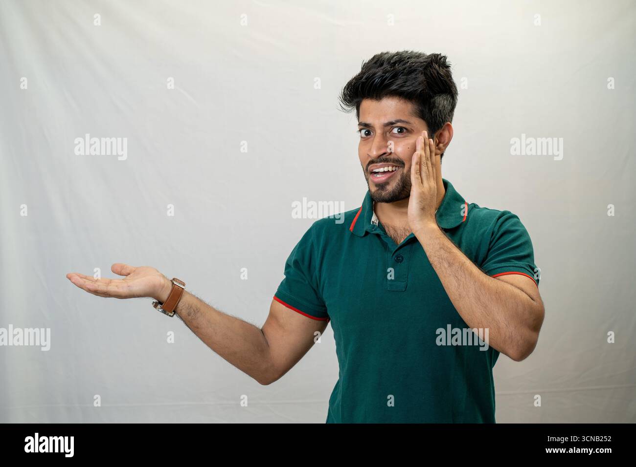 Ein junger Mann mit einem glücklichen und überraschten Ausdruck, der mit einer Hand Gesten macht. Stockfoto