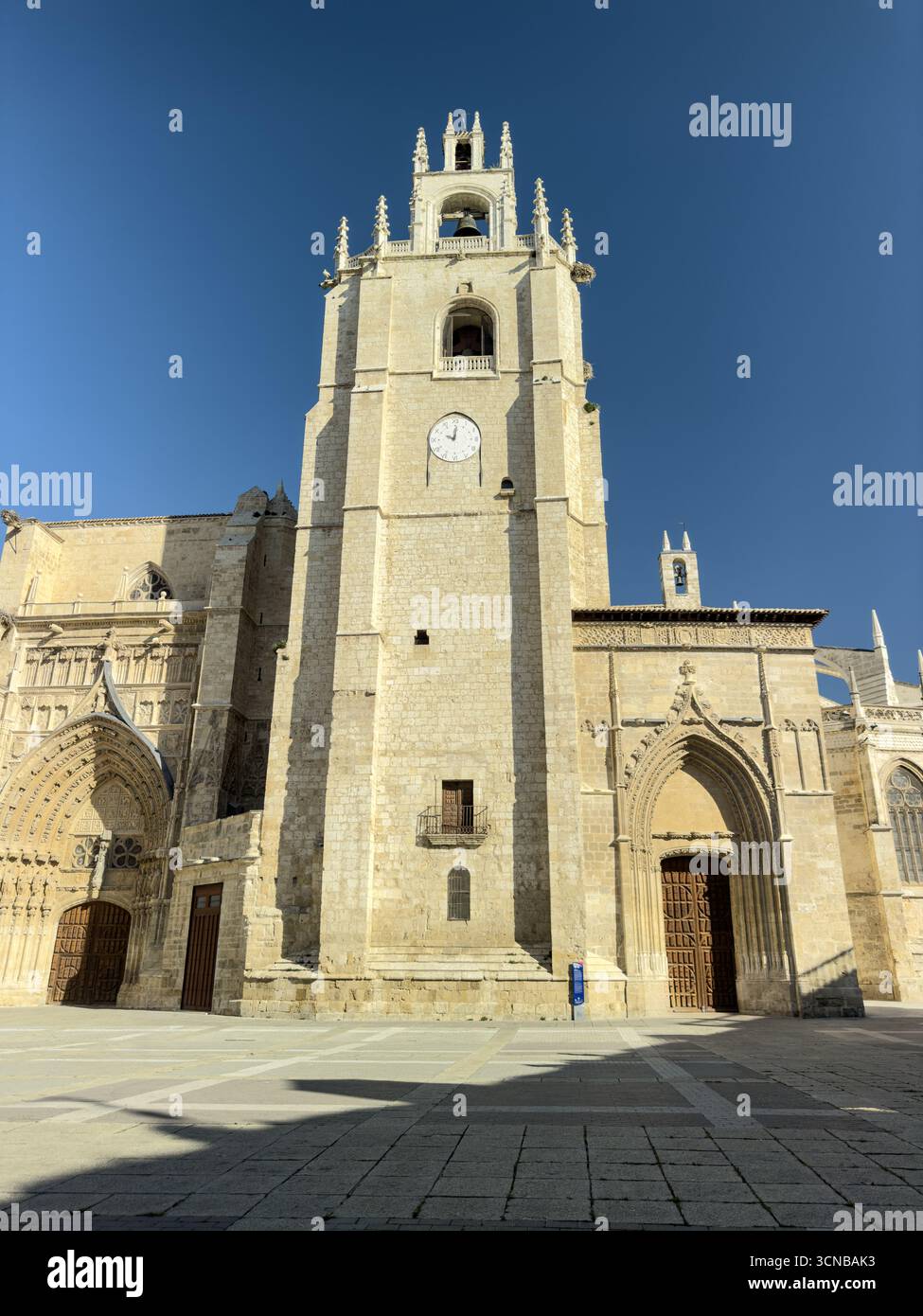 Gotischer Glockenturm der Kathedrale von Palencia mit Uhr, Türmen und reich detaillierten Eingangsbögen Stockfoto