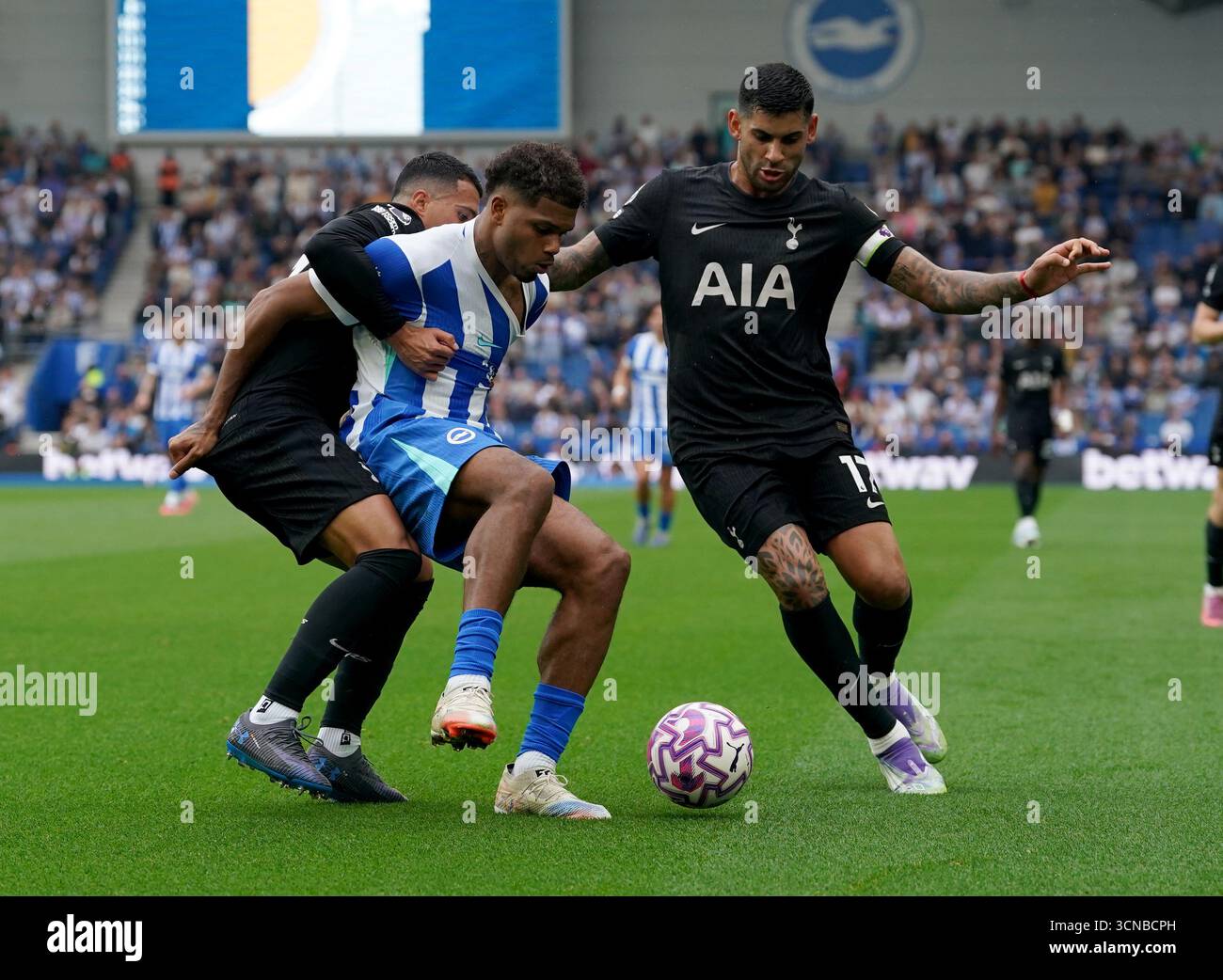 Brighton und Hove Albions Georginio Rutter (Mitte) kämpfen um den Ball mit Tottenham Hotspurs Pedro Porro (links) und Tottenham Hotspurs Cristian Romero (rechts) während des Premier League-Spiels im American Express Stadium in Brighton. Bilddatum: Samstag, 20. September 2025. Stockfoto