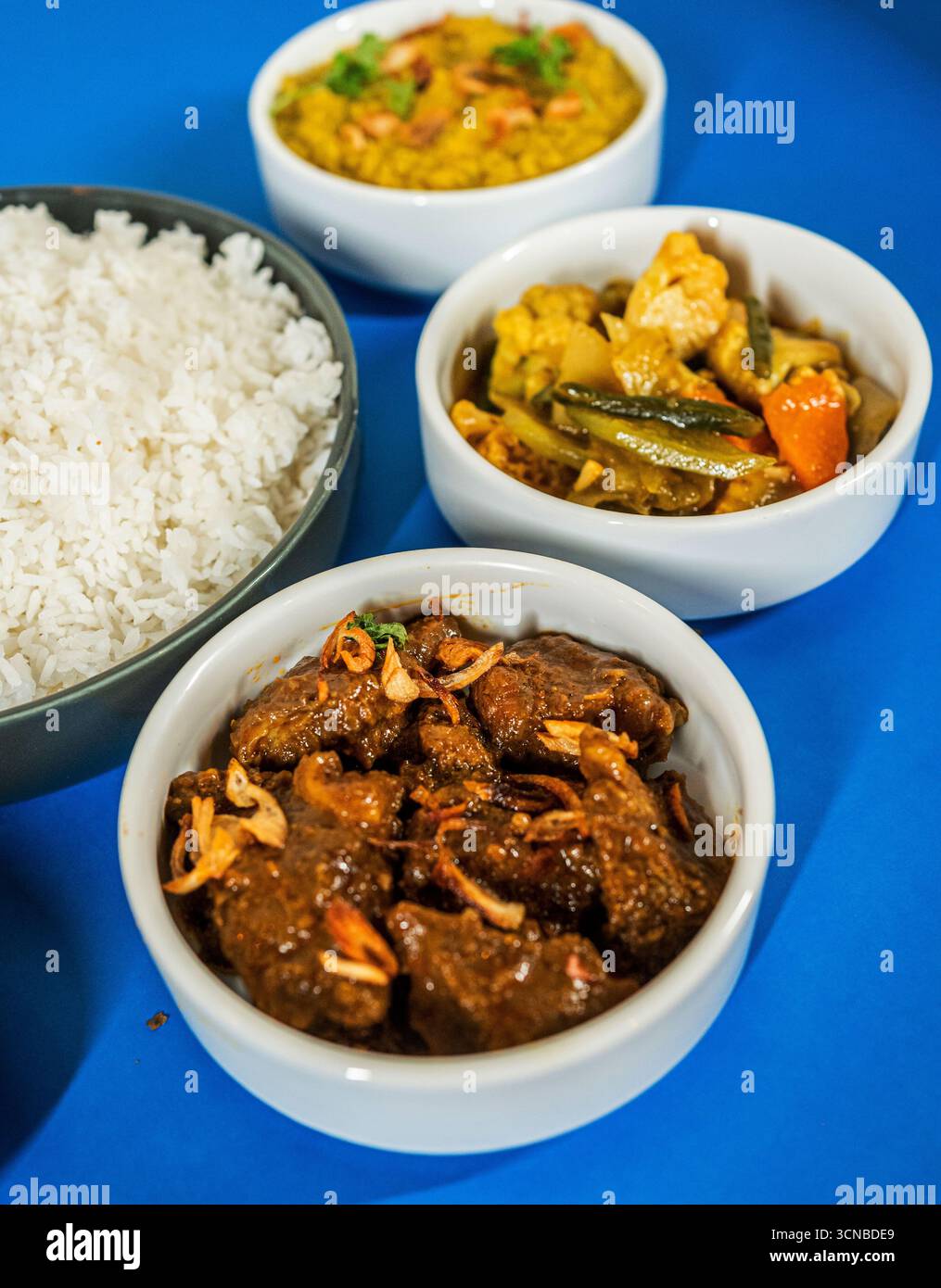 Ein großer Nahaufnahme eines Tellers asiatischer Speisen mit einer Portion gebratenem Reis, einem Rührbraten mit Fleisch und Gemüse und in Scheiben geschnittenen Gurken. Stockfoto
