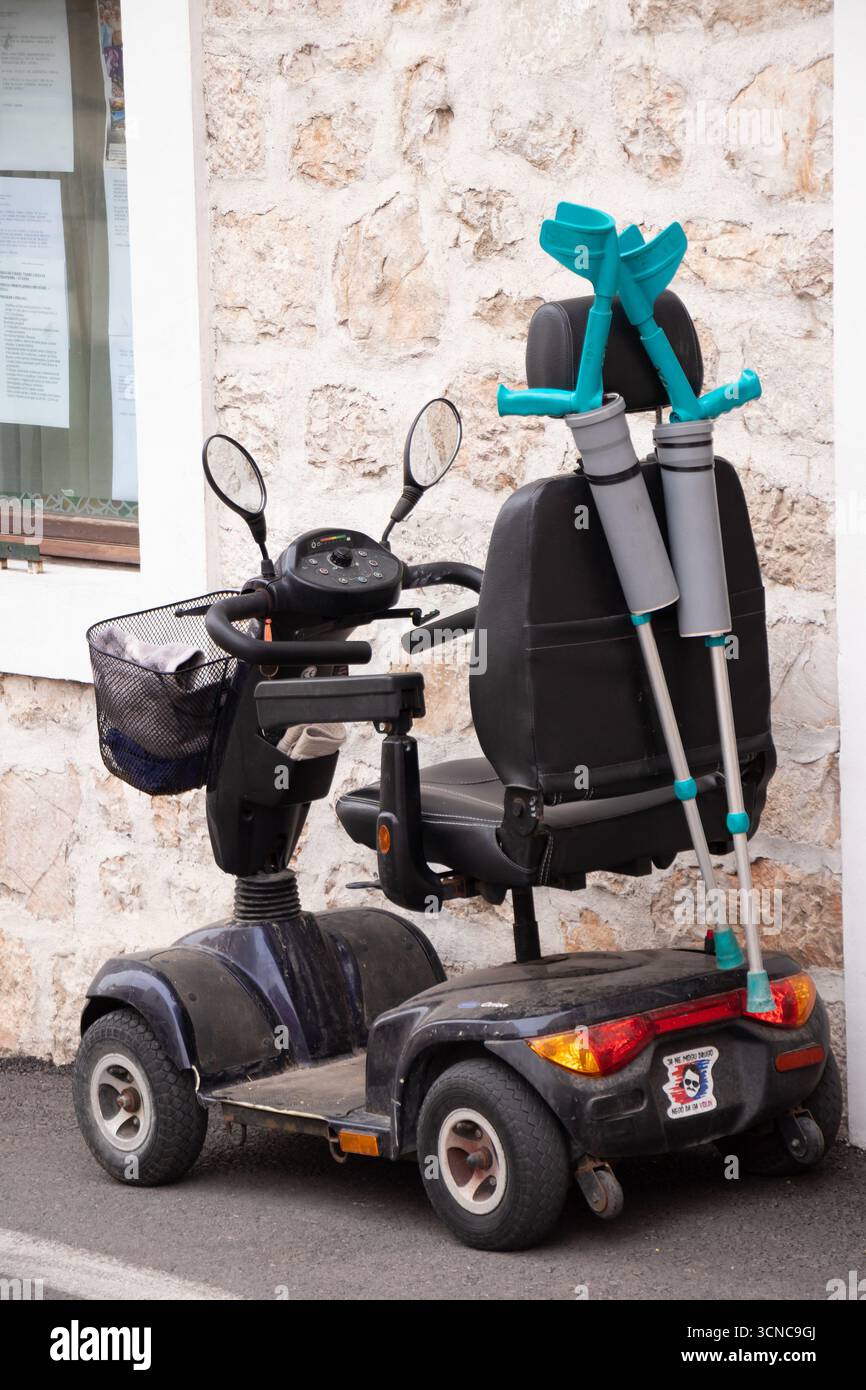 Vodice, Kroatien - 7. September 2025: Ein älterer Allrad-Roller mit zwei Krücken parkt auf der Straße vor dem Haus Stockfoto