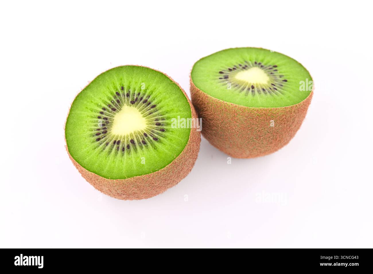 Zwei Kiwis werden in zwei Hälften geschnitten und auf einem weißen Hintergrund platziert. Die Kiwis sind grün und haben schwarze Samen Stockfoto
