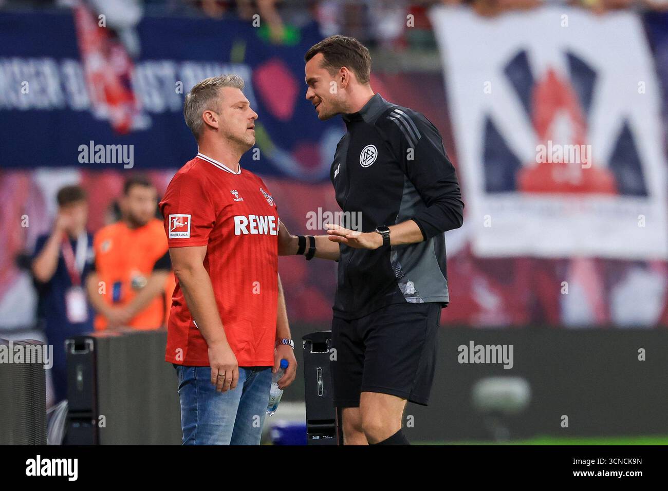 Leipzig, Deutschland. September 2025. Fußball: Bundesliga, RB Leipzig - 1. FC Köln, Spieltag 4, Red Bull Arena. Der 4. Offizielle Richard Hempel versichert Trainer Lukas Kwasniok (1. FC Köln). Hinweis: Jan Woitas/dpa - WICHTIGER HINWEIS: Gemäß den Vorschriften der DFL Deutschen Fußball-Liga und des DFB Deutschen Fußball-Bundes ist es verboten, im Stadion und/oder des Spiels aufgenommene Fotografien in Form von sequenziellen Bildern und/oder videoähnlichen Fotoserien zu verwenden oder zu verwenden./dpa/Alamy Live News Stockfoto