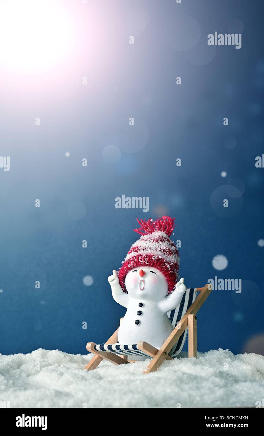 Ein kleiner Schneemänner auf der Sonne länger in Hüllen auf Schnee im Winter. Festlicher Hintergrund mit einem lustigen Schneemann. Weihnachtskarte, Kopierraum. Stockfoto