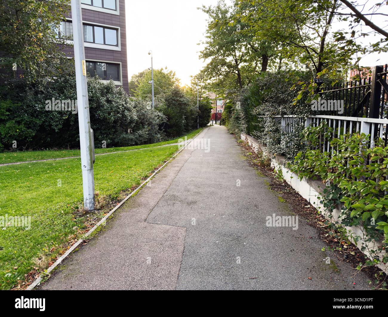 Städtischer Pfad umgeben von Vegetation und Gebäuden unter einem hellen Manchester-Himmel Stockfoto