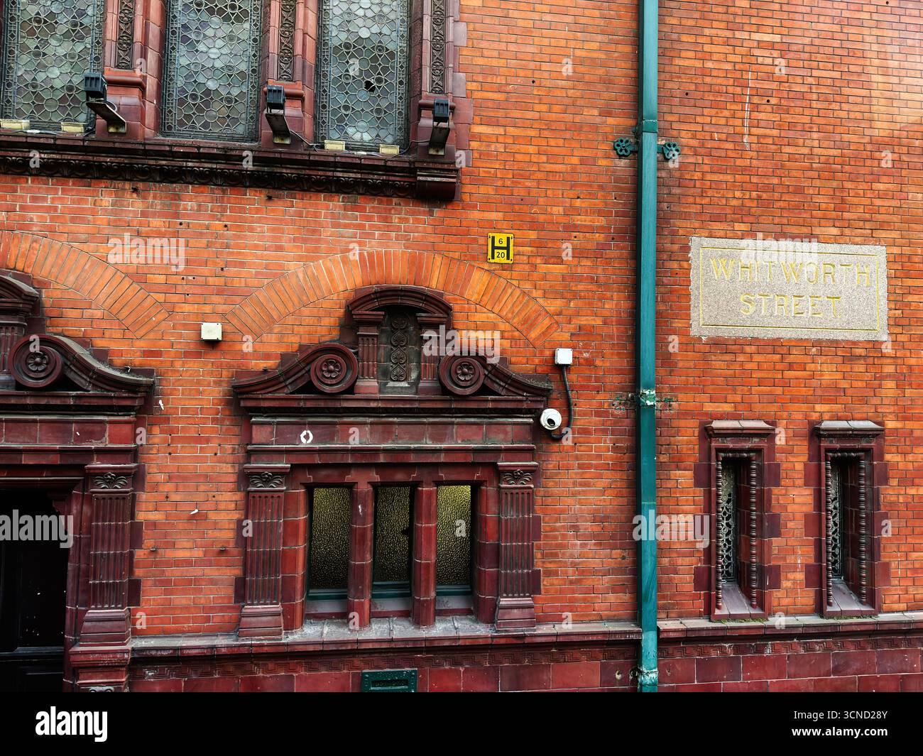 Rote Ziegelfassade mit dekorativen Bögen und verzierten Fenstern an der Whitworth Street in Manchester. Stockfoto