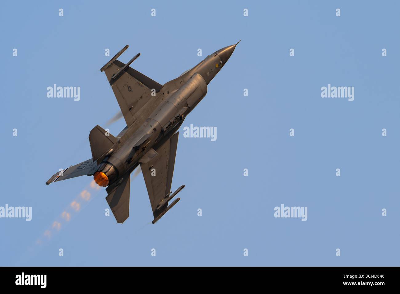 F16 Viper mit Afterburner-Feuer in einem klaren blauen Himmel darüber Stockfoto