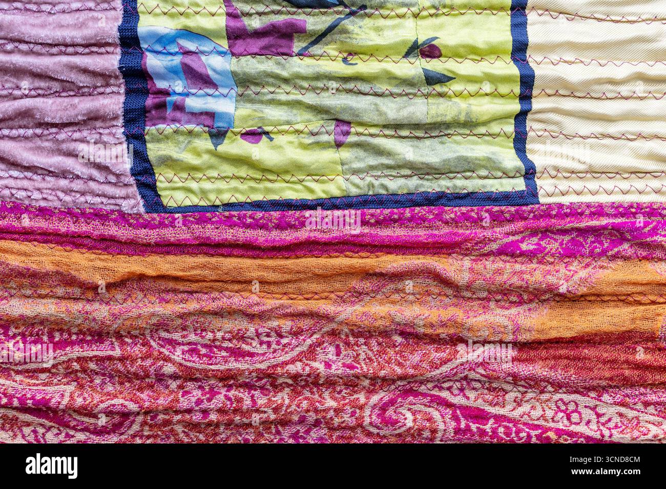 Textiler Hintergrund – strukturierte Oberfläche aus gefaltetem Seidenpatchworkgewebe in Nahaufnahme Stockfoto
