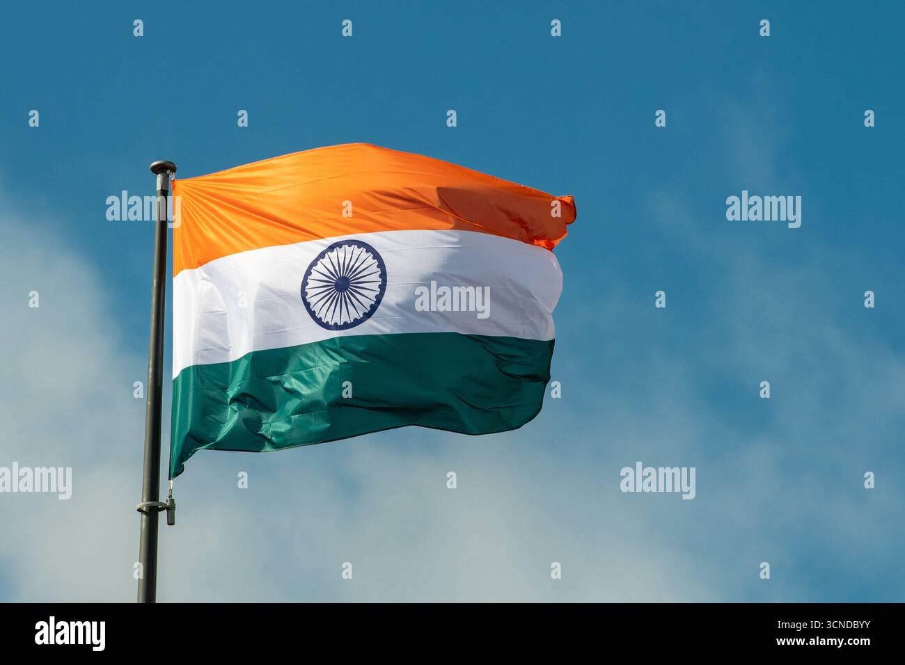 Die wunderschöne indische Nationalflagge winkt im Wind vor einem klaren blauen Himmel. Die dreifarbige Flagge ist mit Safran-, weißen und grünen Streifen versehen Stockfoto