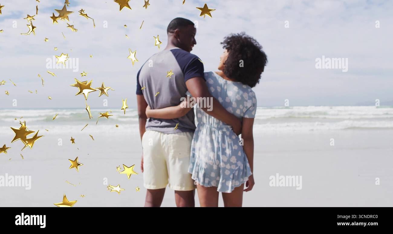 Stehend erwachsenes Paar mit Taille am Sandstrand, mit dekorativen goldenen Sternformen Stockfoto