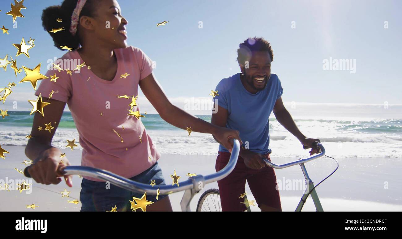Spazierendes Paar mit rosa, blauen T-Shirts und Shorts, die Fahrräder entlang der nassen Küste schieben, Wellen Stockfoto