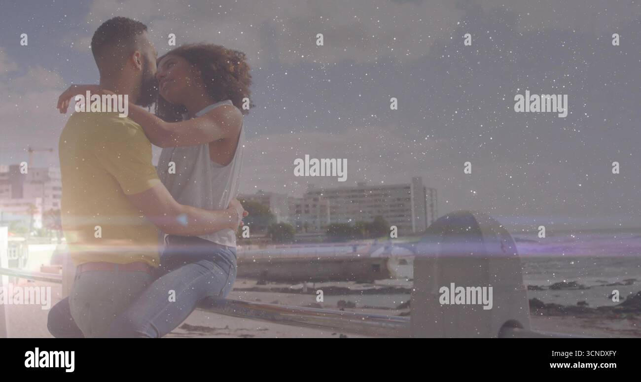 Umarmendes Paar, das auf einem Metallgeländer über der Ufermauer sitzt, mit Wasser- und Stadtgebäuden, Kopierraum Stockfoto