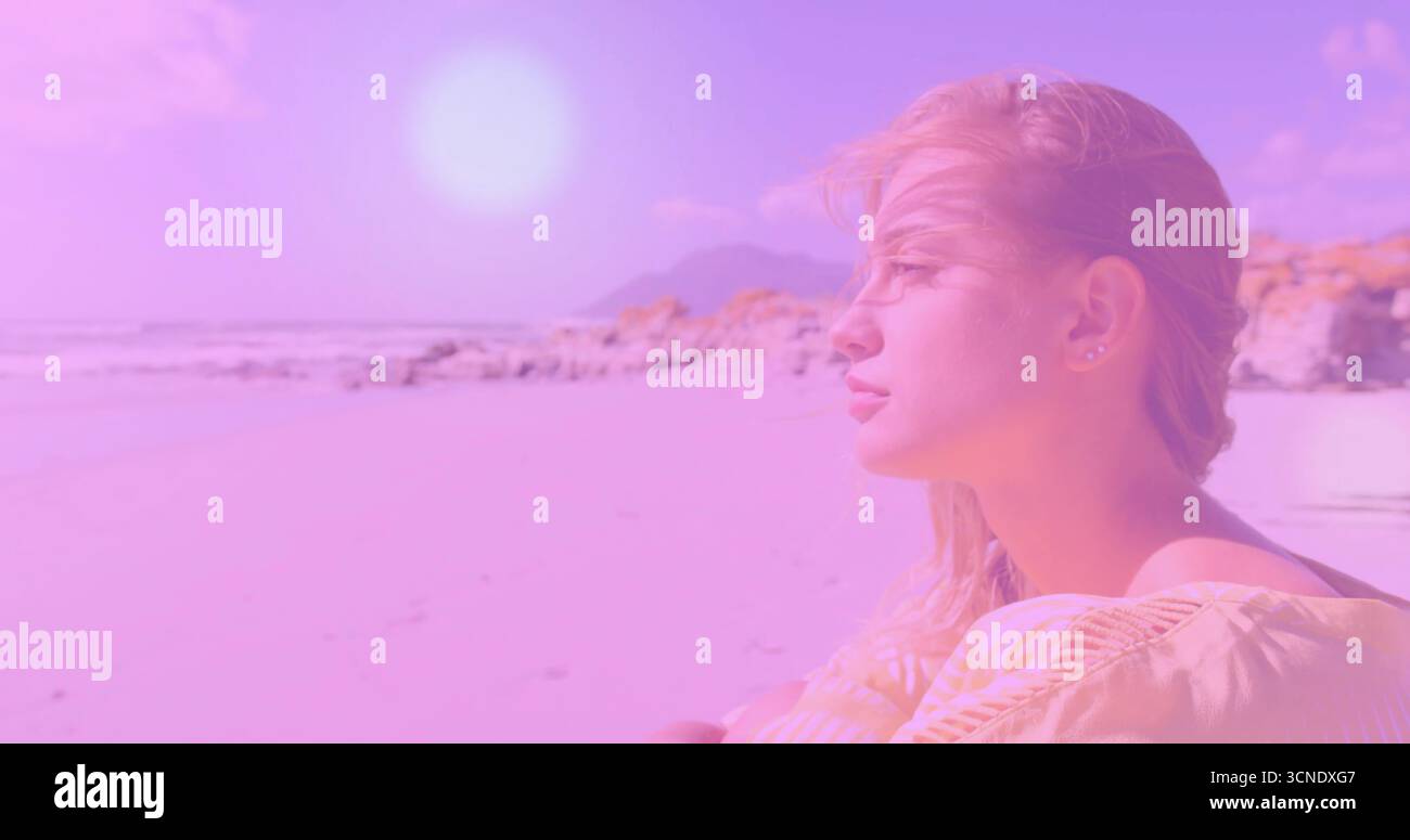 Eine Frau in gelbem Off-Shoulder-Top, die am Strand in der Nähe von Felsvorsprüngen und Wellen sitzt, Kopierraum Stockfoto