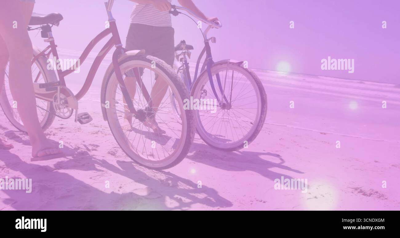 Zwei Freunde in Sommerkleid und gestreiftem T-Shirt am Sandstrand stehen, mit Cruiser-Fahrrädern Stockfoto