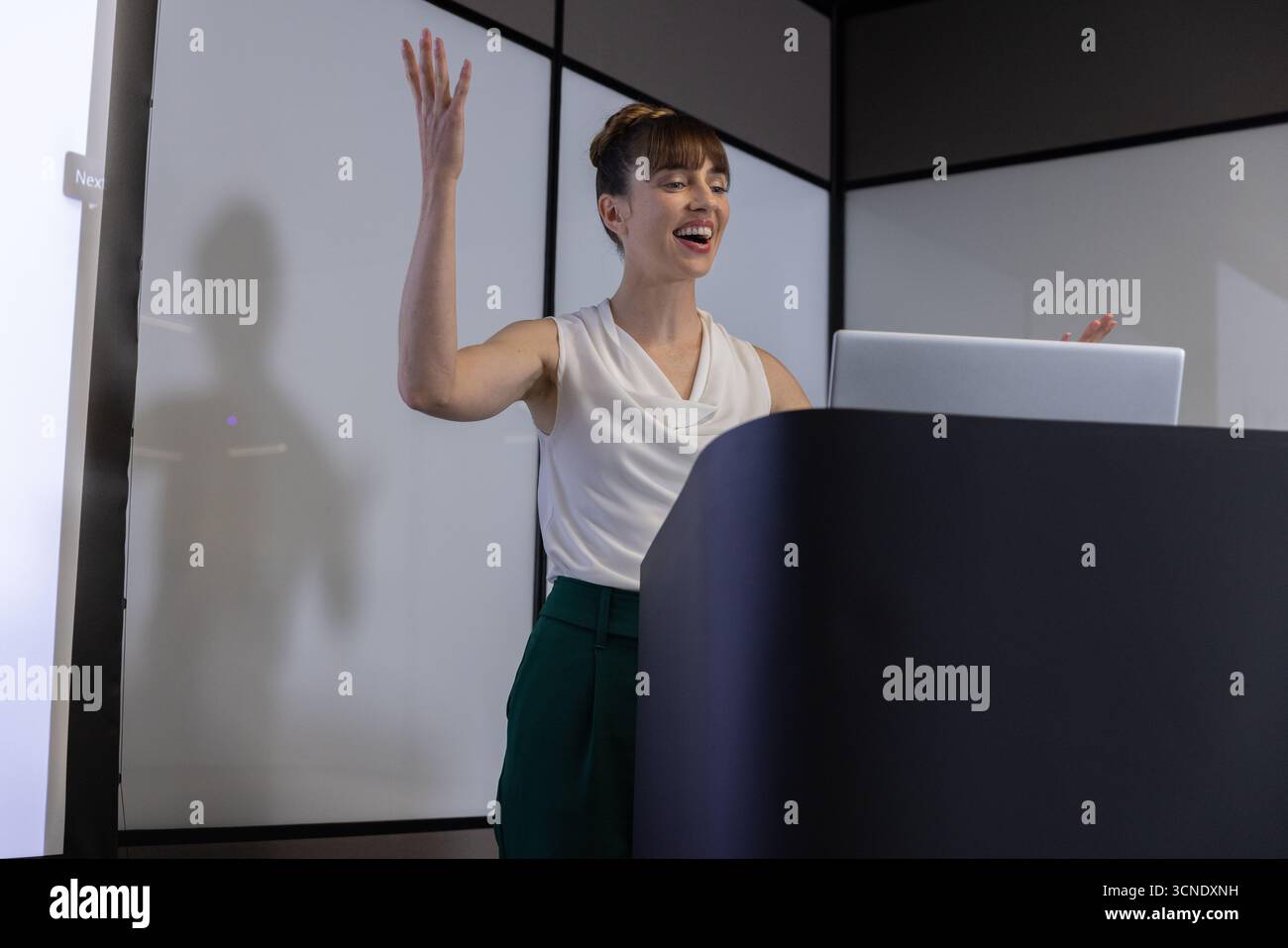 Geschäftsmoderatorin im mittleren Erwachsenenalter mit Gesten auf dem Podium mit Laptop Stockfoto