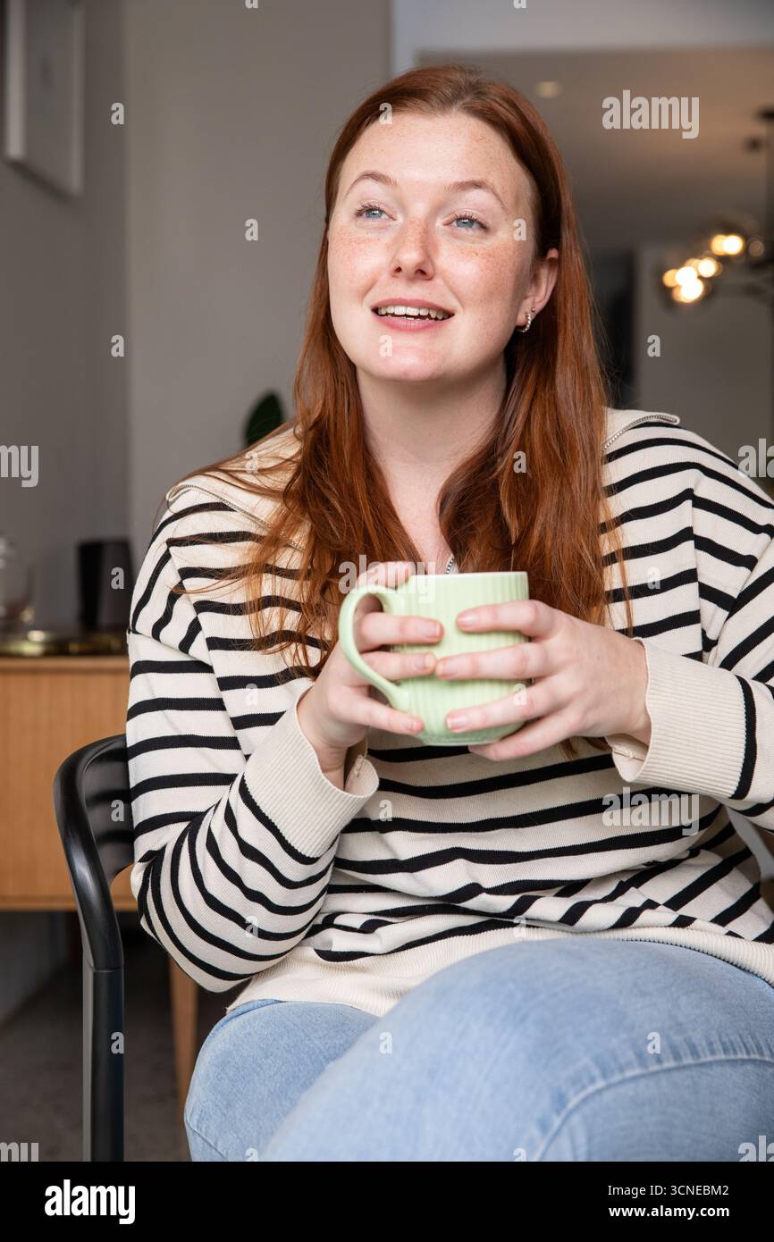 Hellhäutige rothaarige Frau, die im Sessel sitzt und in der Lounge nach oben blickt Stockfoto Hellhäutige rothaarige Frau, die im Sessel sitzt und in der Lounge nach oben blickt Stockfoto