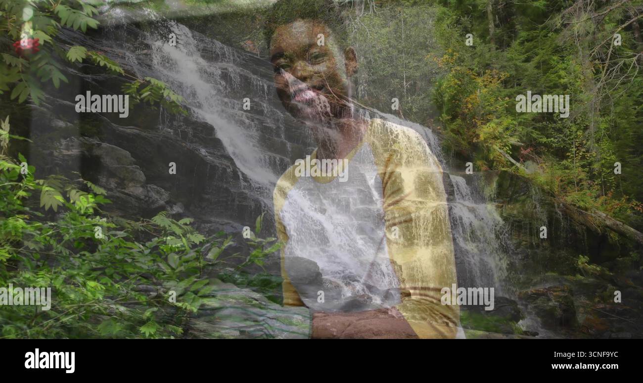Stehende Frau mit gelbem weißem Hemd posiert im Waldwasserfall, mit felsigem Laub Stockfoto