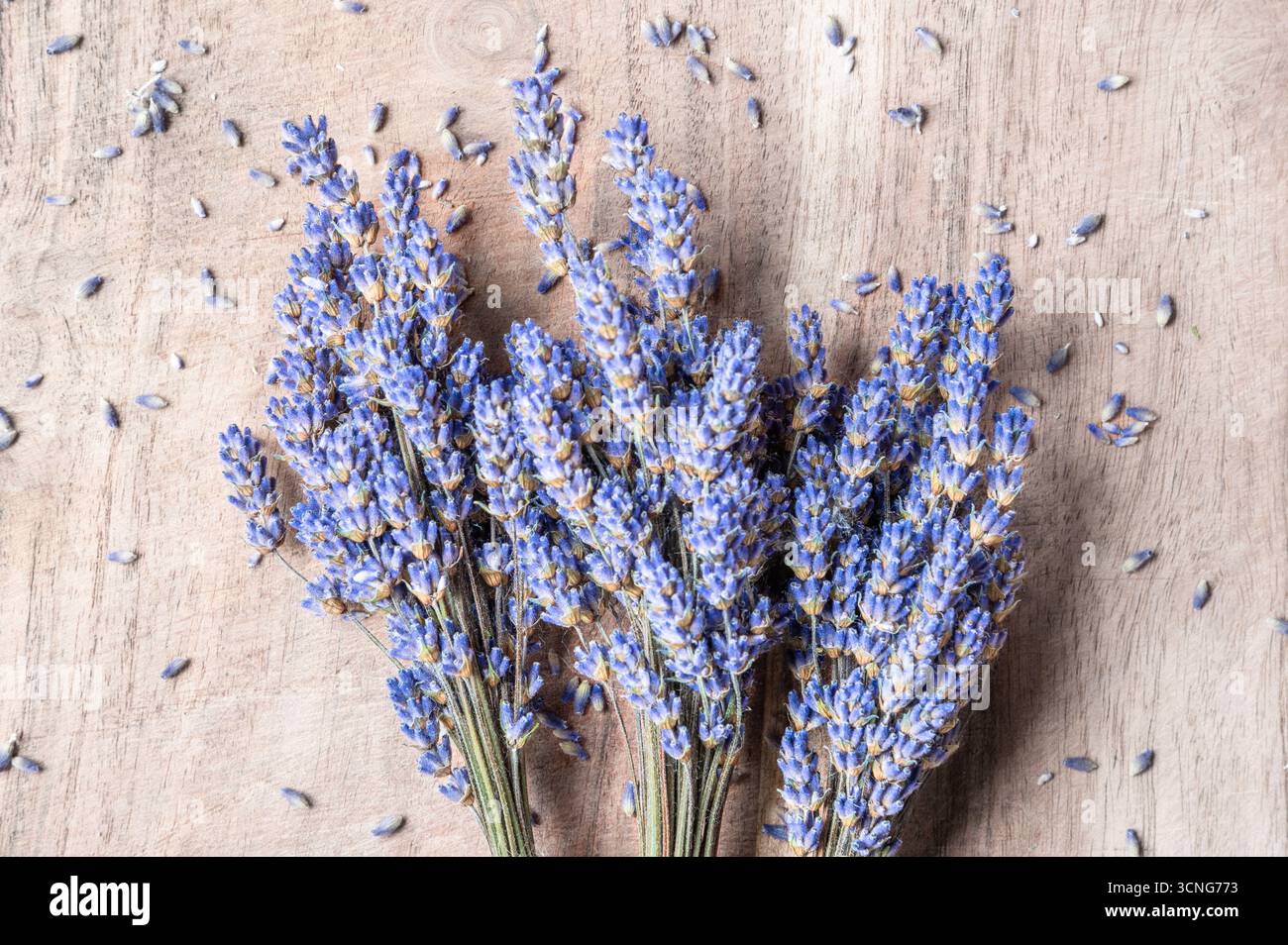 Ein Haufen Lavendelblumen auf einem Holzhintergrund mit verstreuten Lavendelblumen Stockfoto
