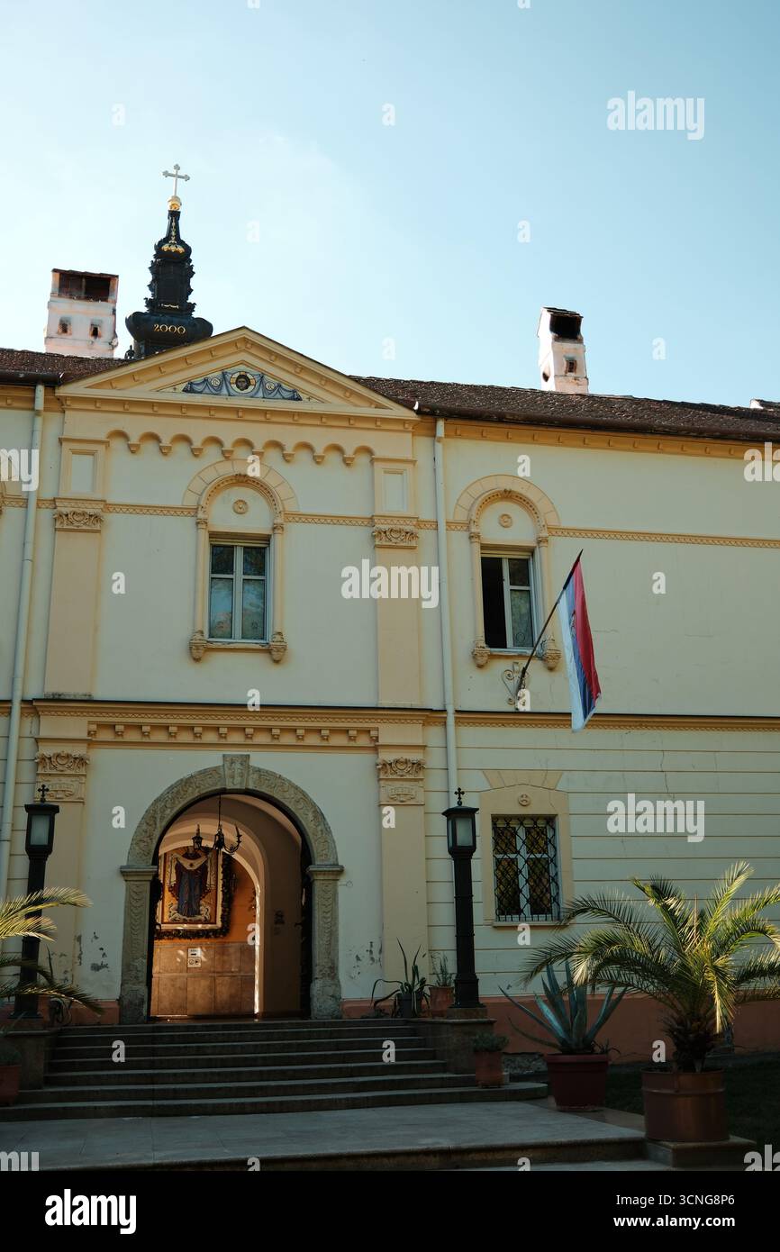 Eingang zum Kloster Grgeteg mit serbischer Flagge, Palmen und historischer Architektur. Novi Sad, Serbien - 19. September 2025. Stockfoto