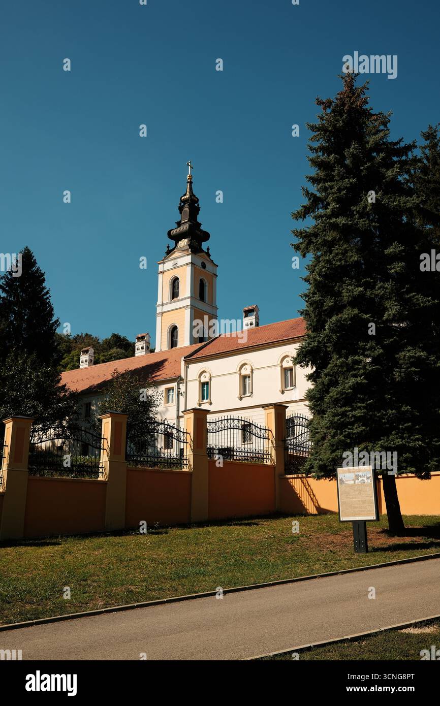 Außenansicht des Klosters Grgeteg und des Turms umgeben von Bäumen und Zaun in Fruska Gora. Novi Sad, Serbien - 19. September 2025. Stockfoto