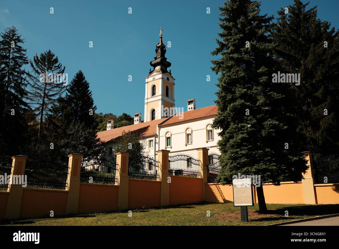 Außenansicht des Klosters Grgeteg und des Turms umgeben von Bäumen und Zaun in Fruska Gora. Novi Sad, Serbien - 19. September 2025. Stockfoto