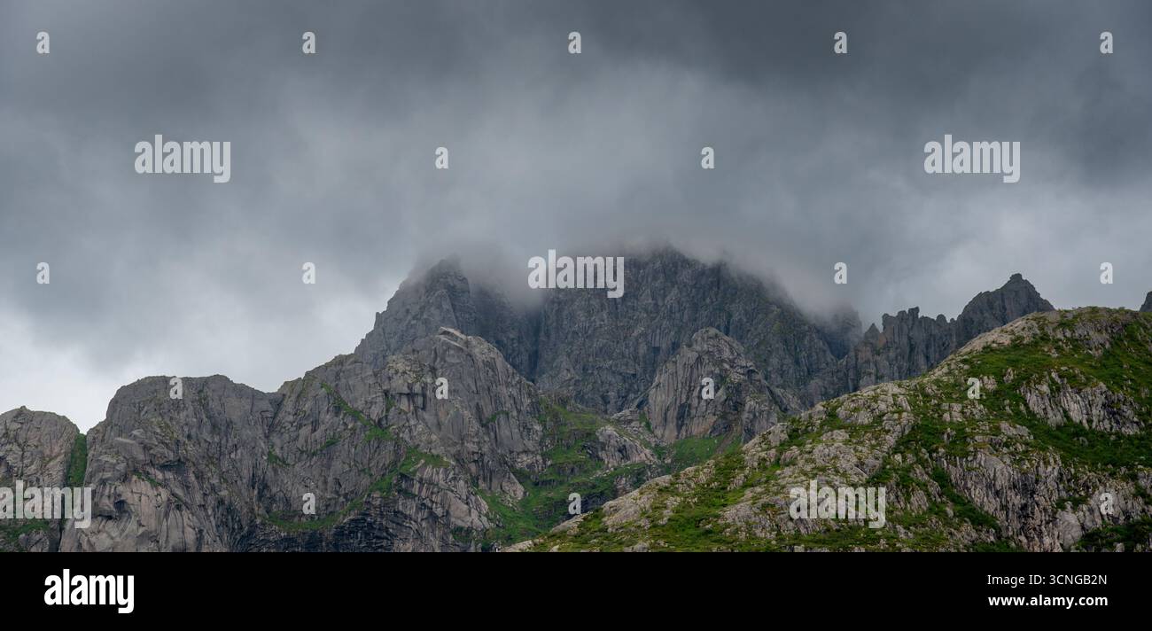 Dunkle Sturmwolken und Nebel umhüllen die scharfen Granitgipfel in Lofoten, Norwegen. Stockfoto