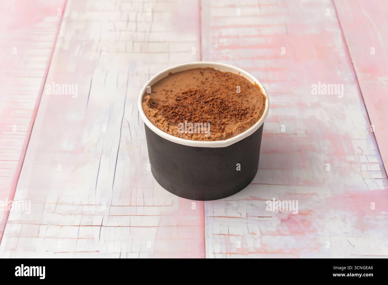 Belgisches Schokoladeneis in einer Wanne mit weißen Schokoladenchips, einem zerbröckelten Keks und einer roten Kirsche darauf, perfekt verarbeitet Stockfoto