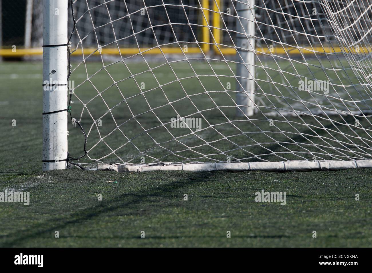 Fußball-Tornetz mit grünem Gras, aus einem niedrigen Winkel gesehen. Stockfoto