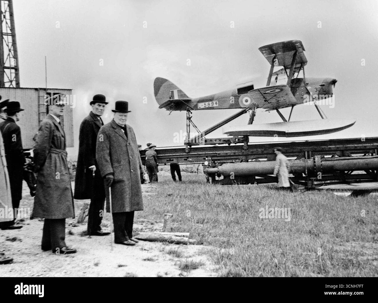 Juni 1941: Winston Churchill und der Kriegsminister warten auf den Start einer funkgesteuerten Zieldrohne de Havilland Queen Bee, 6. Juni 1941. Der Premierminister, Herr Winston Churchill, mit dem ehrenwerten Captain the Right, David Margesson, dem Kriegsminister, beobachtete die Vorbereitungen, die an einem nicht näher bezeichneten Ort des Vereinigten Königreichs für den Start eines de Havilland Queen Bee Wasserflugzeugs L5984 von seiner Rampe aus getroffen wurden. Die pilotlose Zieldrohne Queen Bee war eine funkgesteuerte Version des de Havilland Tiger Moth Trainers - Foto: Geopix/Captain Horton Stockfoto
