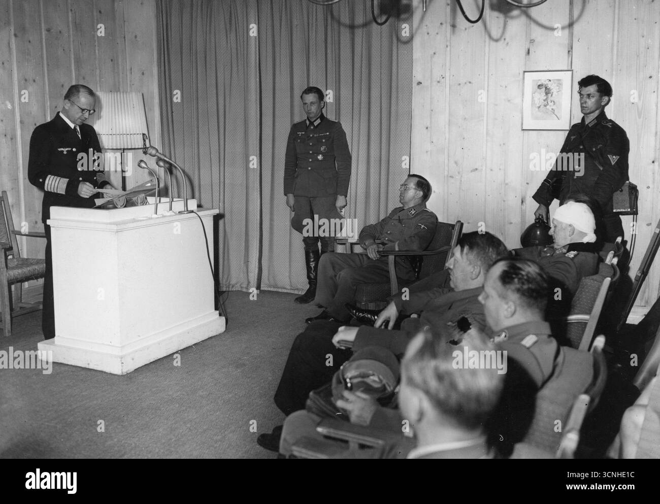 Admiral Karl Donitz hält eine Radiorede nach dem Attentat auf Adolf Hitler. Ebenfalls sichtbar sind Adolf Hitler, Julius Schaub, Martin Bormann, Otto Dietrich und Alfred Jodl (mit einem bandagierten Kopf) 1944 Stockfoto