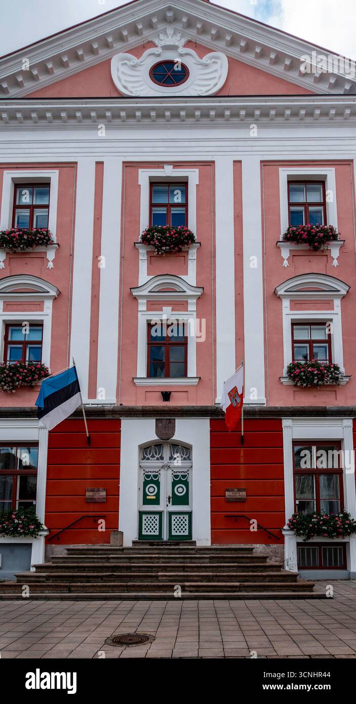 Fassade des Rathauses von Tartu, Estland, mit nationalen und städtischen Flaggen, Blumenkästen und verzierten Eingängen, Heimat der historischen Stadtverwaltung von Tartu. Stockfoto
