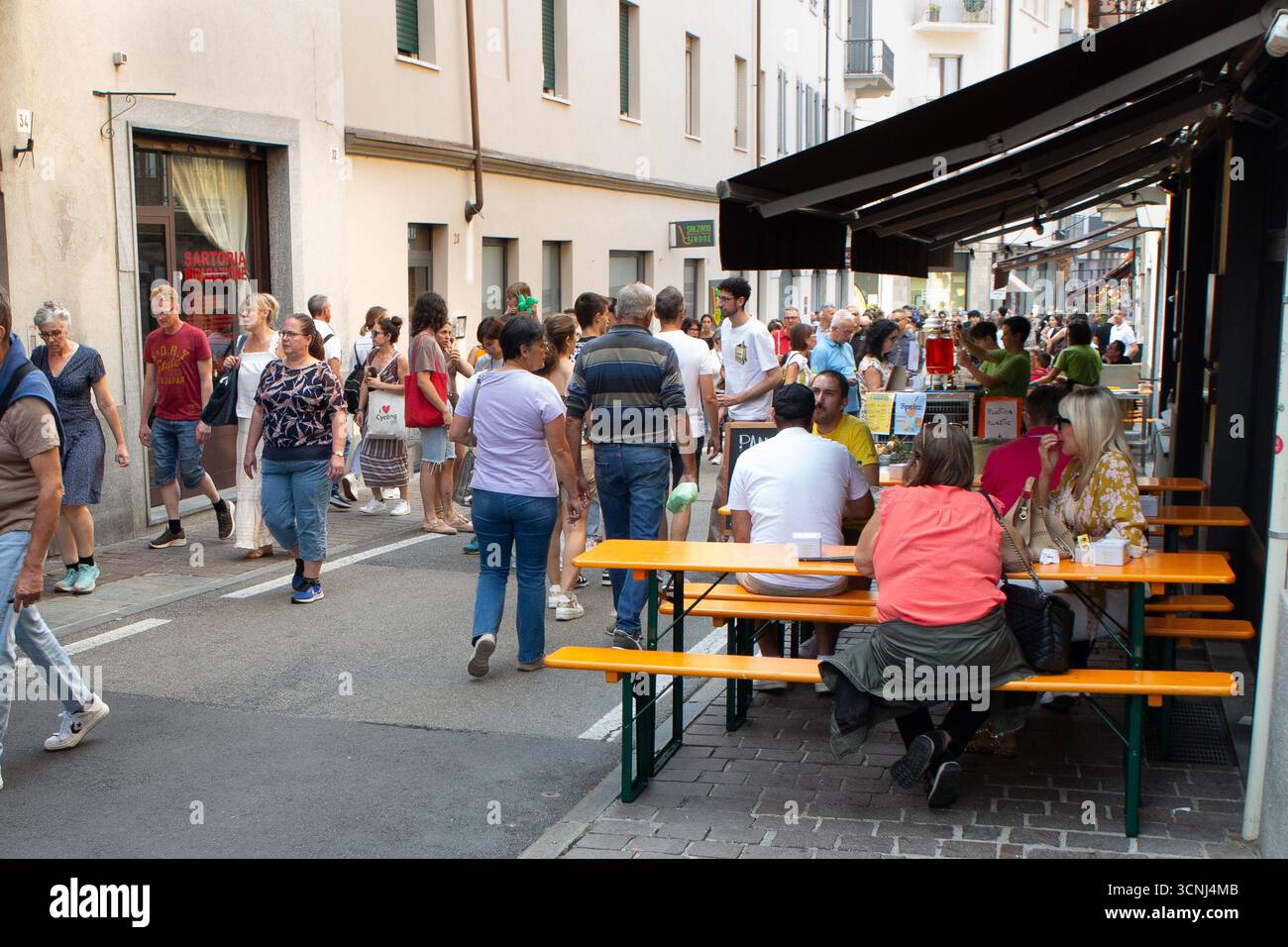Geschäftige Straßenszene mit Outdoor-Dining und Menschenmassen während des Cheese 2025 Slow Food Festivals in Bra. Besucher genießen Speisen an Picknicktischen, während sie Th erkunden Stockfoto