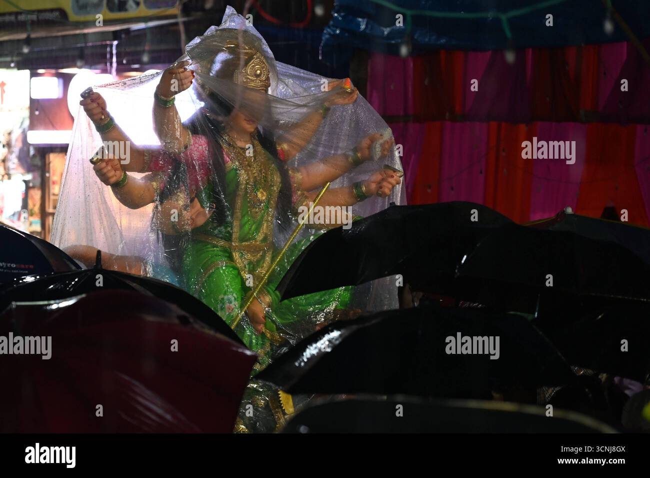 Navi MUMBAI, INDIEN – 21. SEPTEMBER: Devotees trugen das Göttin Durga-Idol mit unerschütterlicher Hingabe durch den strömenden Regen, in Richtung des Pandals, inmitten von Gesängen und Feierlichkeiten auf dem Koperkhairne Market, am 21. September 2025 in Navi Mumbai, Indien. Foto: Bachchan Kumar/Hindustan Times Vorbereitung des Durga Puja Festivals Stockfoto