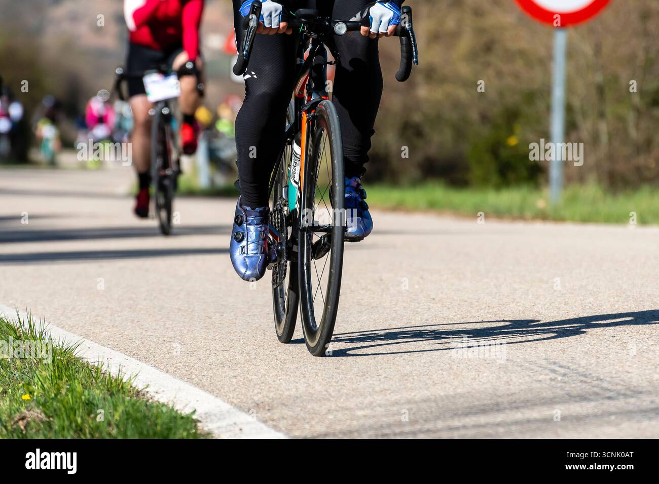Radfahrer, die an einem Frühlingstag auf einer sonnigen Straße an einem Rennen teilnehmen Stockfoto