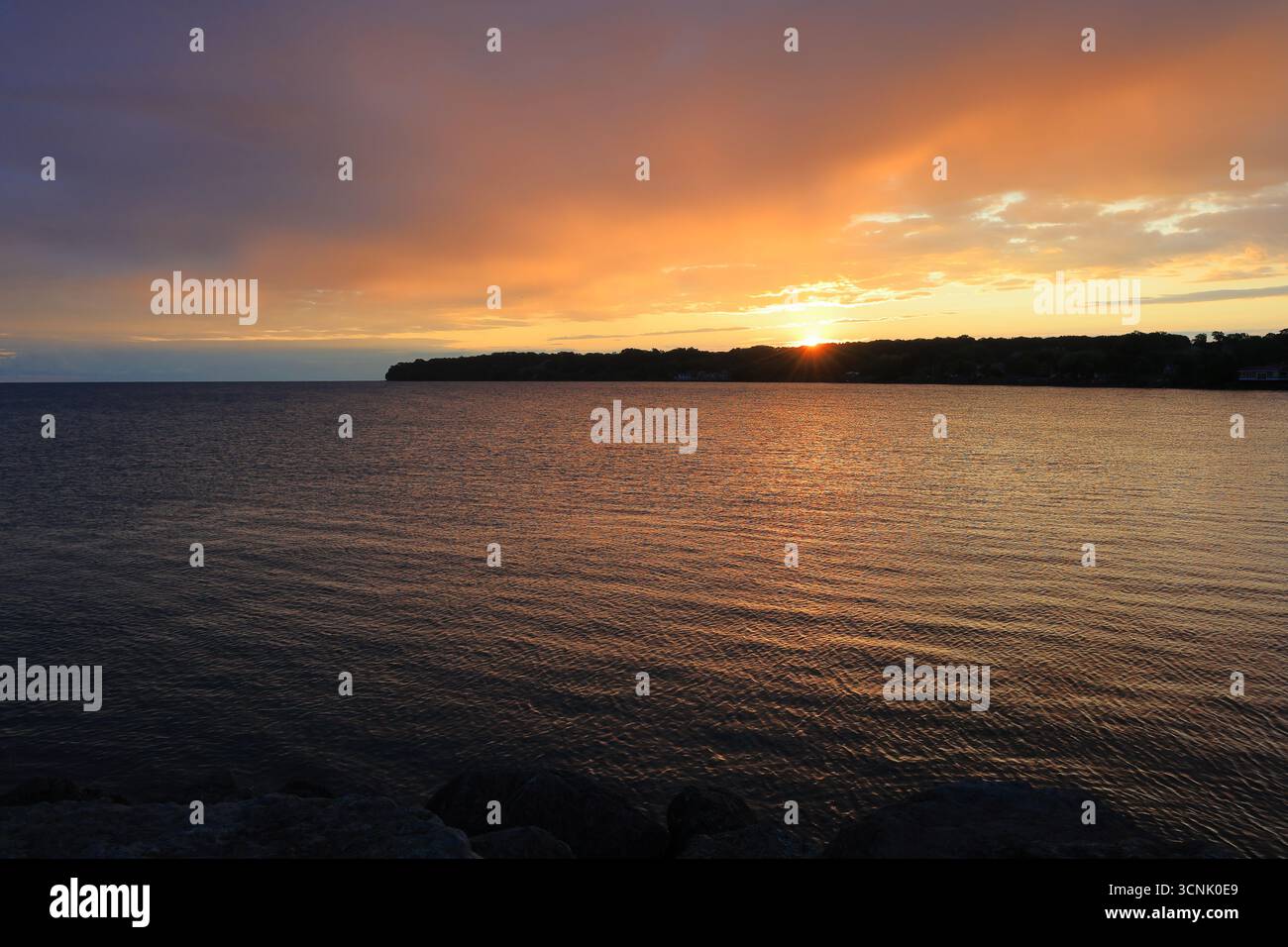 Wunderschöner Sonnenaufgang über einem großen See zeigt an einem klaren Morgen fesselnde Farben Stockfoto