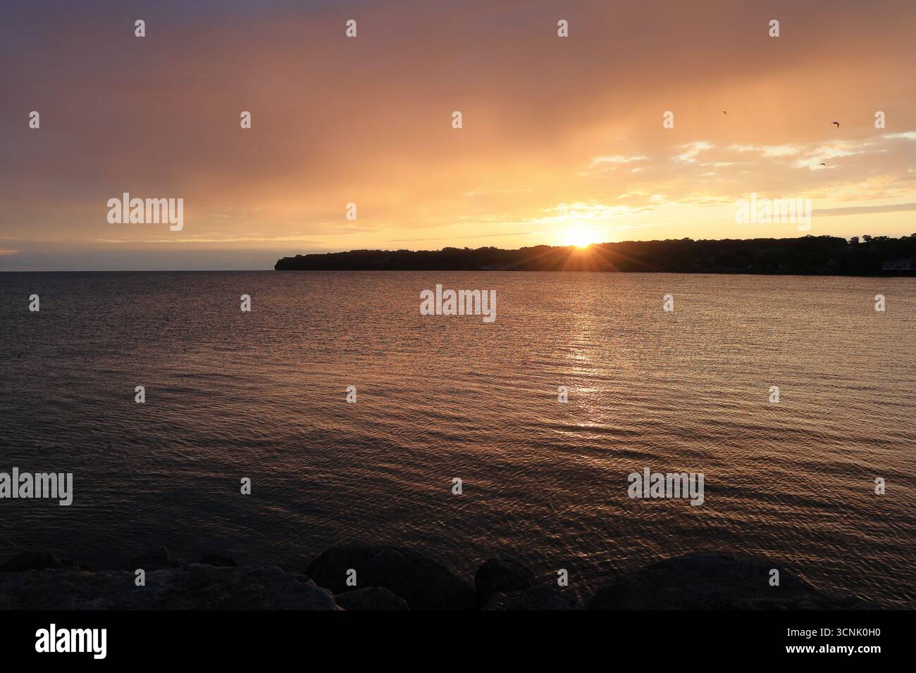 Wunderschöner Sonnenaufgang über einem großen See zeigt an einem klaren Morgen fesselnde Farben Stockfoto