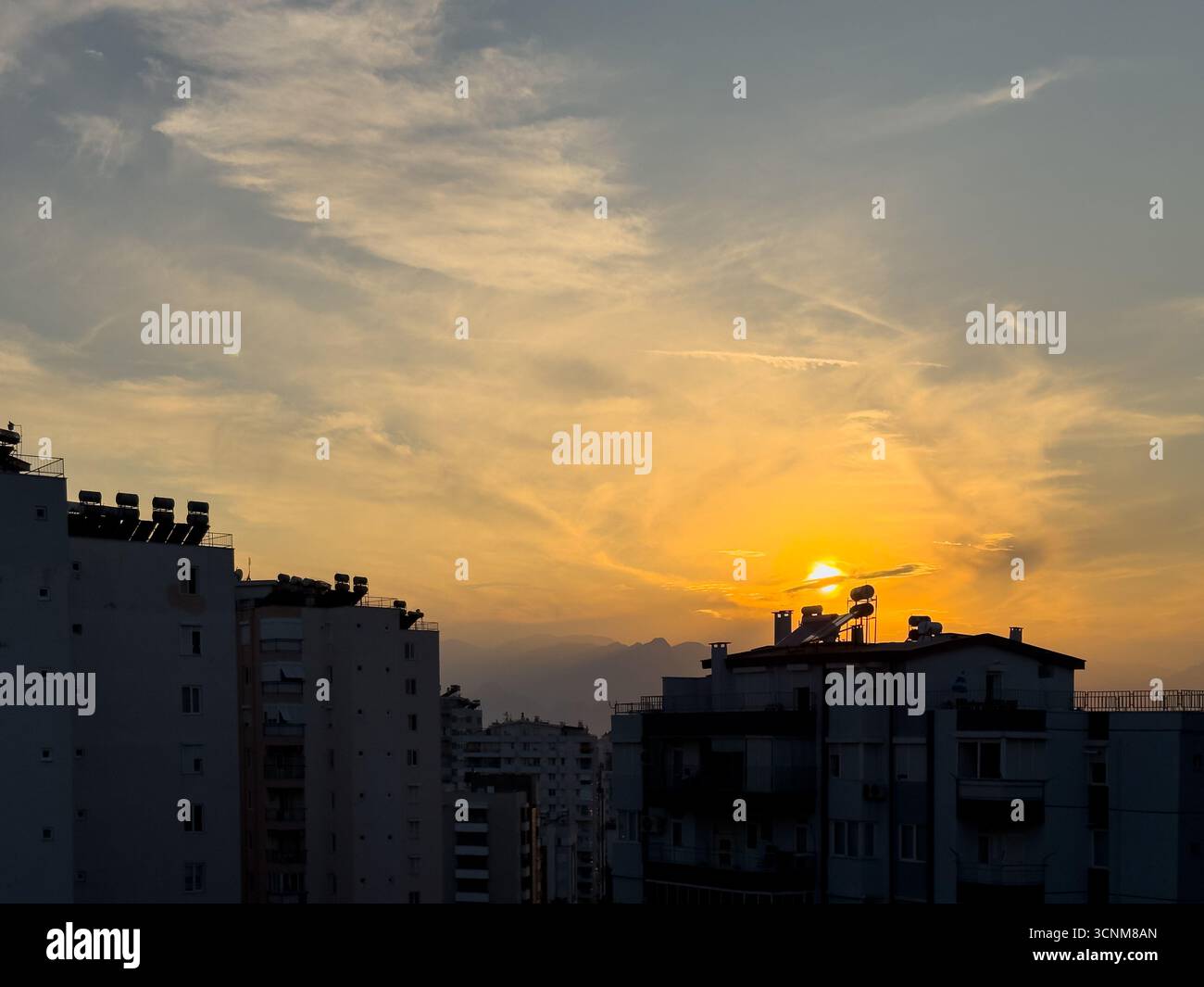 Sonnenuntergang über der Skyline der Stadt mit Silhouetten und warmem Himmel Stockfoto