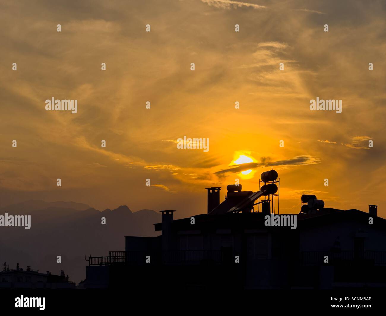 Dramatische Silhouette auf dem Dach vor feurigem Sonnenuntergang über der Stadt Stockfoto