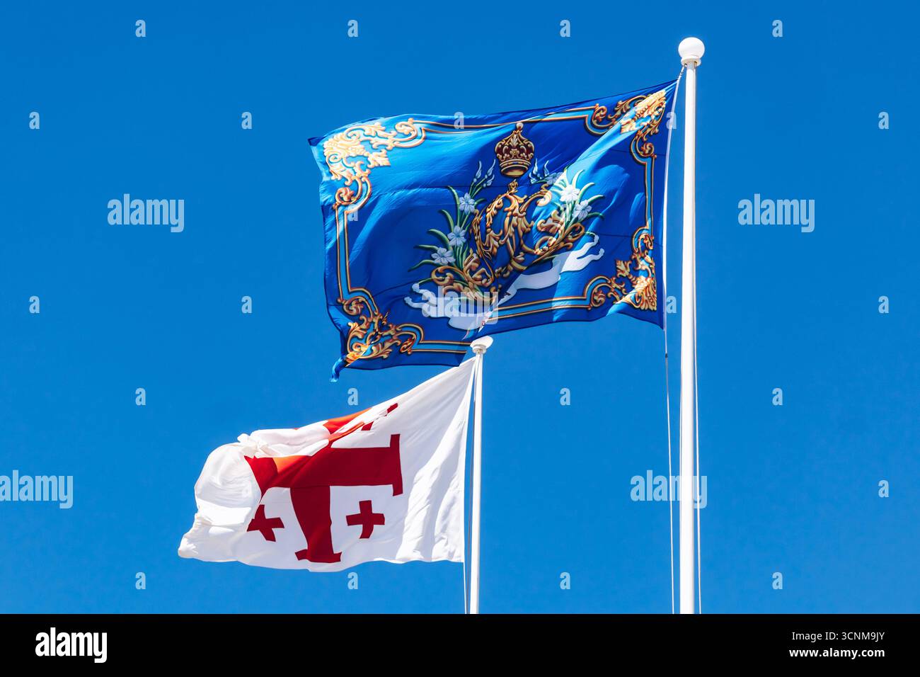 Die blaue Flagge des Großmeisters des Souveränen Malteserordens und die weiße Flagge des Malteserordens (Jerusalemer Kreuz) winkten gegen A Stockfoto