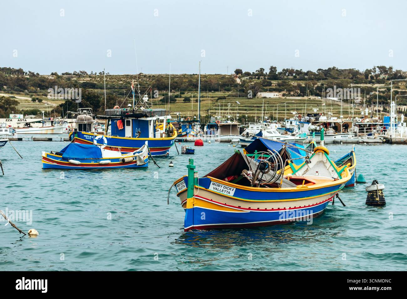 Marsaxlokk, Malta - 13. April 2025: Traditionelle, farbenfrohe maltesische Fischerboote, genannt Luzzu, mit leuchtend blauen, gelben und roten Details, die in der verankert sind Stockfoto