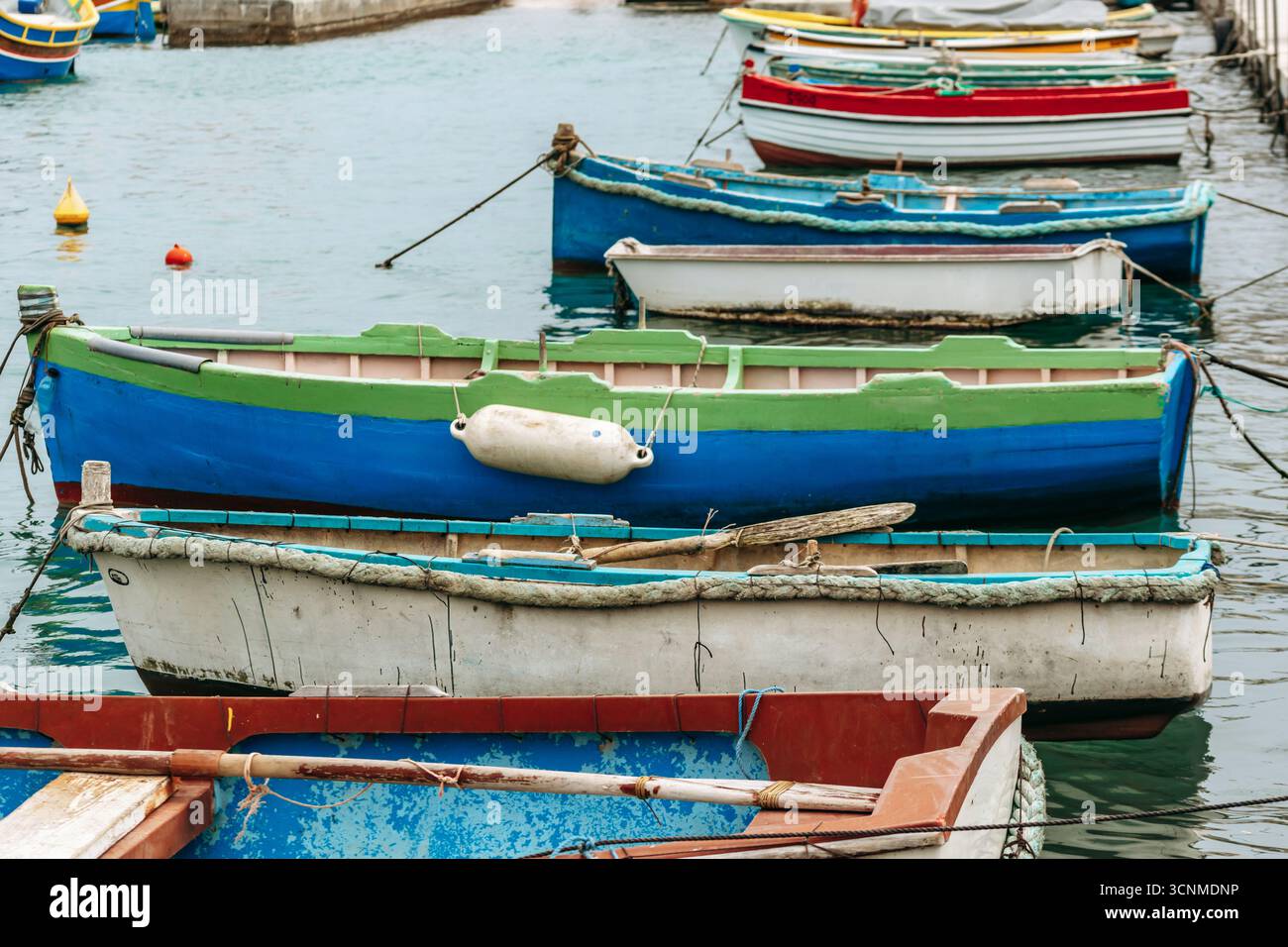 Marsaxlokk, Malta - 13. April 2025: Traditionelle, farbenfrohe maltesische Fischerboote, genannt Luzzu, mit leuchtend blauen, gelben und roten Details, die in der verankert sind Stockfoto