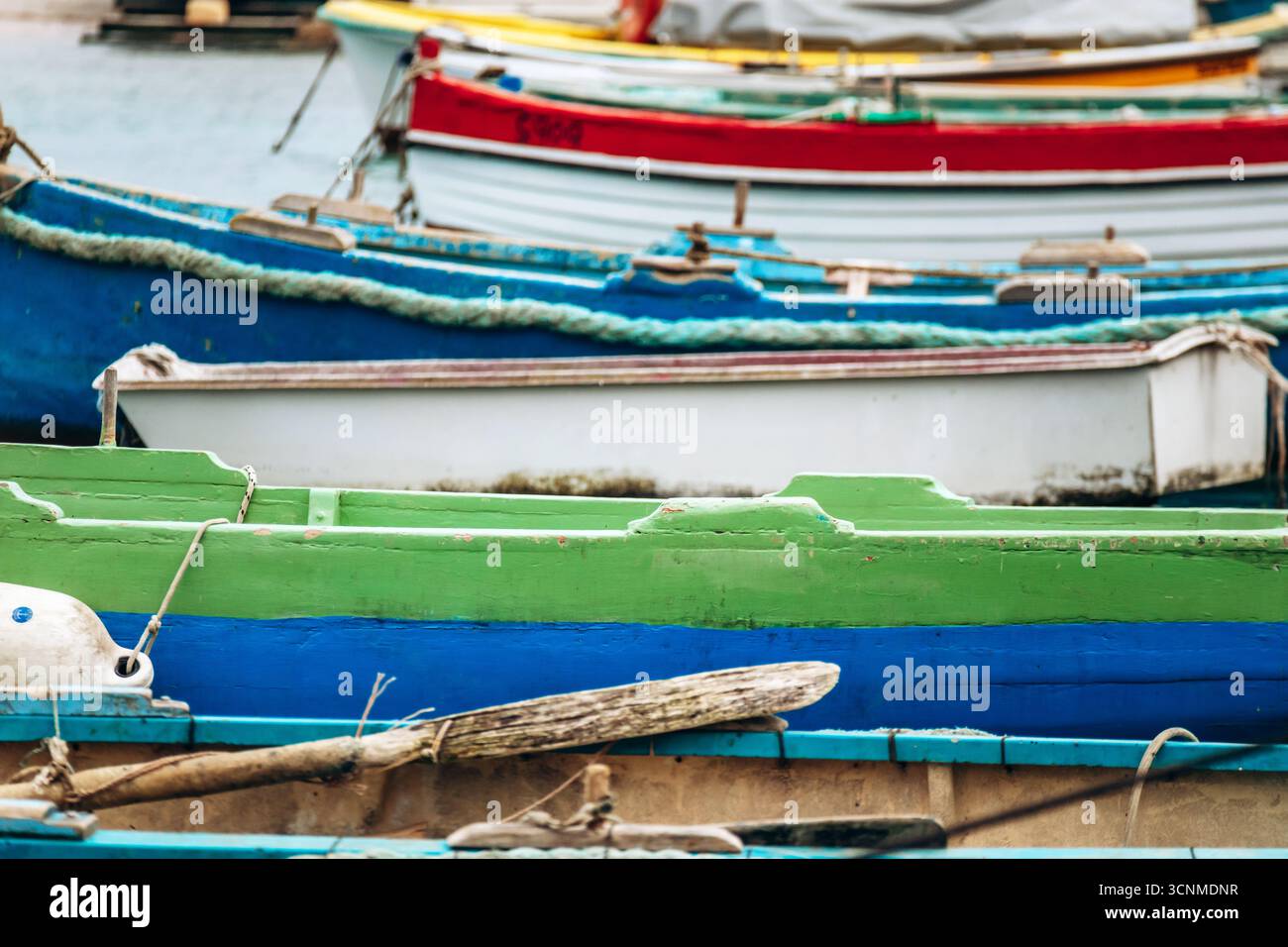 Marsaxlokk, Malta - 13. April 2025: Traditionelle, farbenfrohe maltesische Fischerboote, genannt Luzzu, mit leuchtend blauen, gelben und roten Details, die in der verankert sind Stockfoto