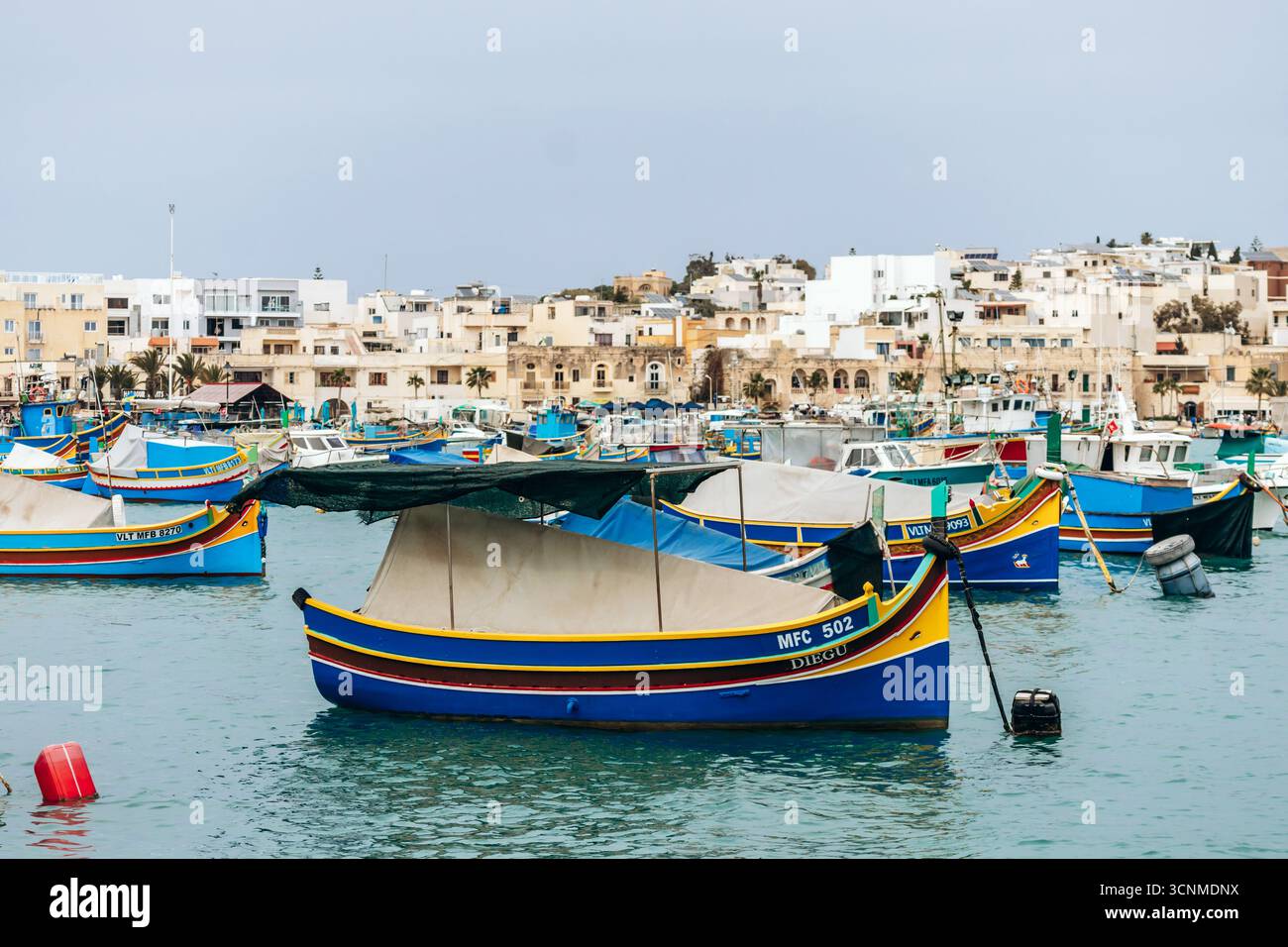 Marsaxlokk, Malta - 13. April 2025: Traditionelle, farbenfrohe maltesische Fischerboote, genannt Luzzu, mit leuchtend blauen, gelben und roten Details, die in der verankert sind Stockfoto