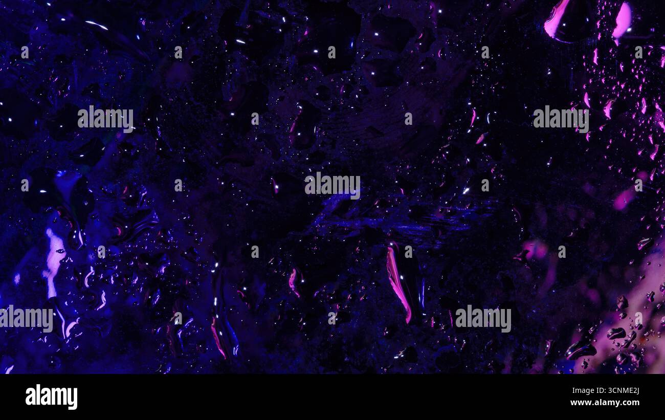 Abstrakte Makroaufnahme aus nassem Glas mit tiefvioletten und violetten Neonlichtreflexionen, mit verstreuten Wassertröpfchen und Flüssigkeitsabstrichen. Stockfoto