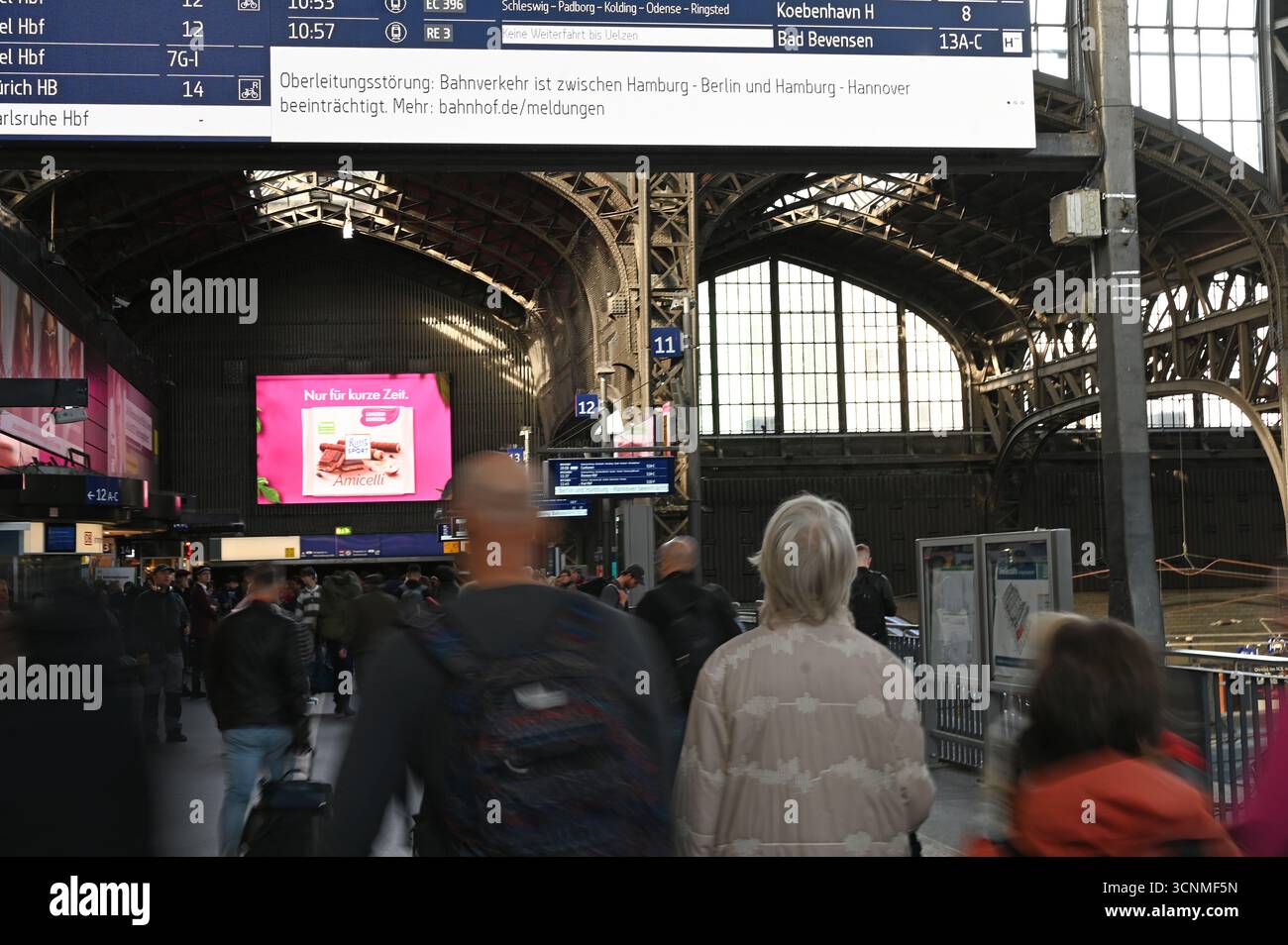Hamburg, Deutschland. September 2025. Reisende gehen am Hamburger Hauptbahnhof zu Fuß, während eine Bahnstation der Deutschen Bahn einen Fahrleitungsfehler anzeigt. Eine gebrochene Freileitung führte heute Morgen zu starken Einschränkungen des Eisenbahnverkehrs im Norden. Quelle: David Hammersen/epa AAP/dpa/Alamy Live News Stockfoto