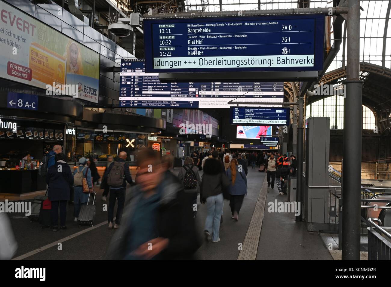 Hamburg, Deutschland. September 2025. Reisende gehen am Hamburger Hauptbahnhof zu Fuß, während eine Bahnstation der Deutschen Bahn einen Fahrleitungsfehler anzeigt. Eine gebrochene Freileitung führte heute Morgen zu starken Einschränkungen des Eisenbahnverkehrs im Norden. Quelle: David Hammersen/epa AAP/dpa/Alamy Live News Stockfoto