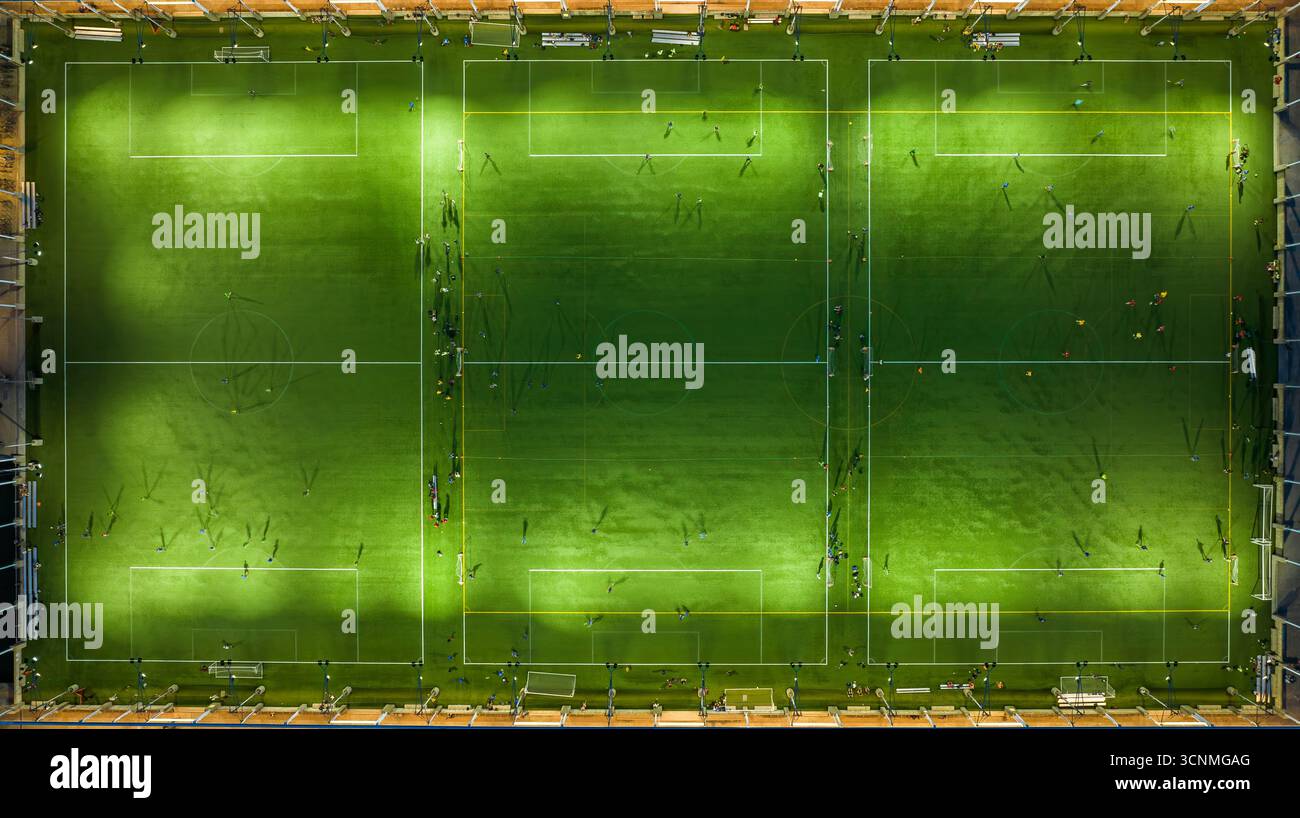 Luftaufnahme mehrerer Spiele, die sich auf einem lebhaften grünen Rasen entfalten, beleuchtet von hellen Deckenleuchten, Manhattan, New York, USA. Stockfoto