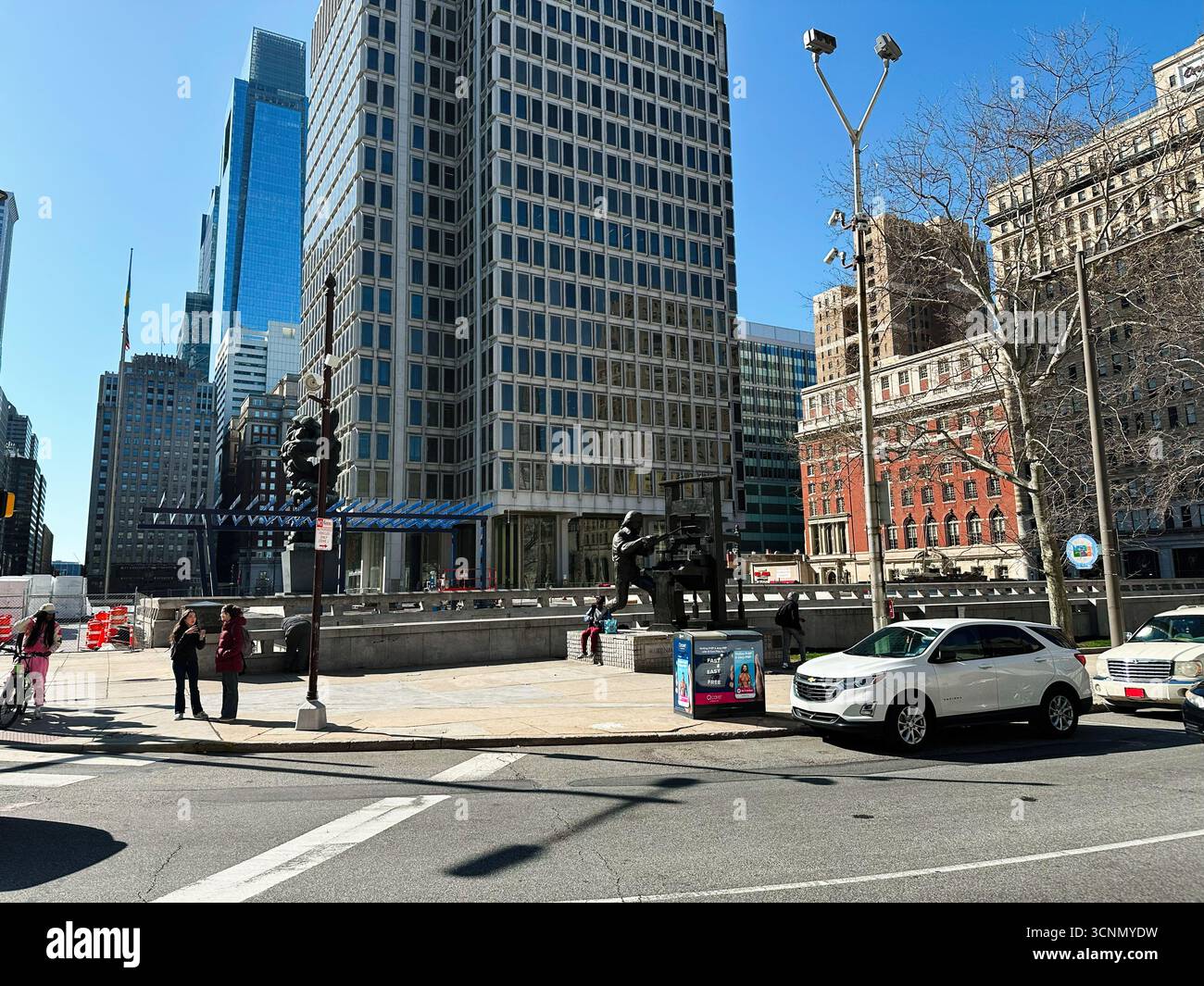 Philadelphia, Pennsylvania, USA - 29. April 2025: Geschäftige urbane Szene im Philadelphia Municipal Services Building mit Hochhäusern, Skulpturen, Autos, Stockfoto