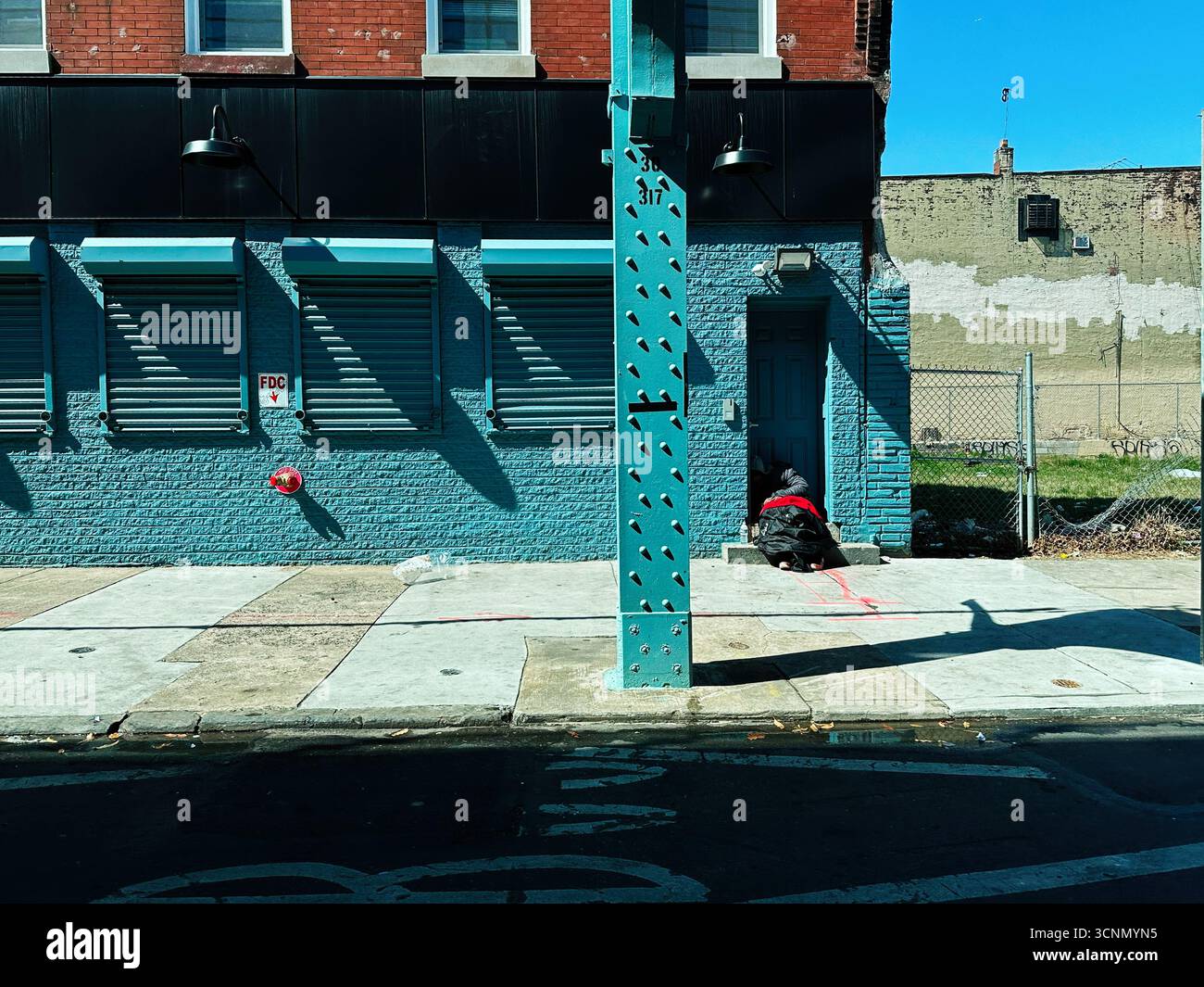 Philadelphia, Pennsylvania, USA - 29. April 2025: Blaue Backsteinfläche auf einem sonnigen Zombieland, Kensington Ave, Philadelphia Street; ein hockendes Zuhause Stockfoto