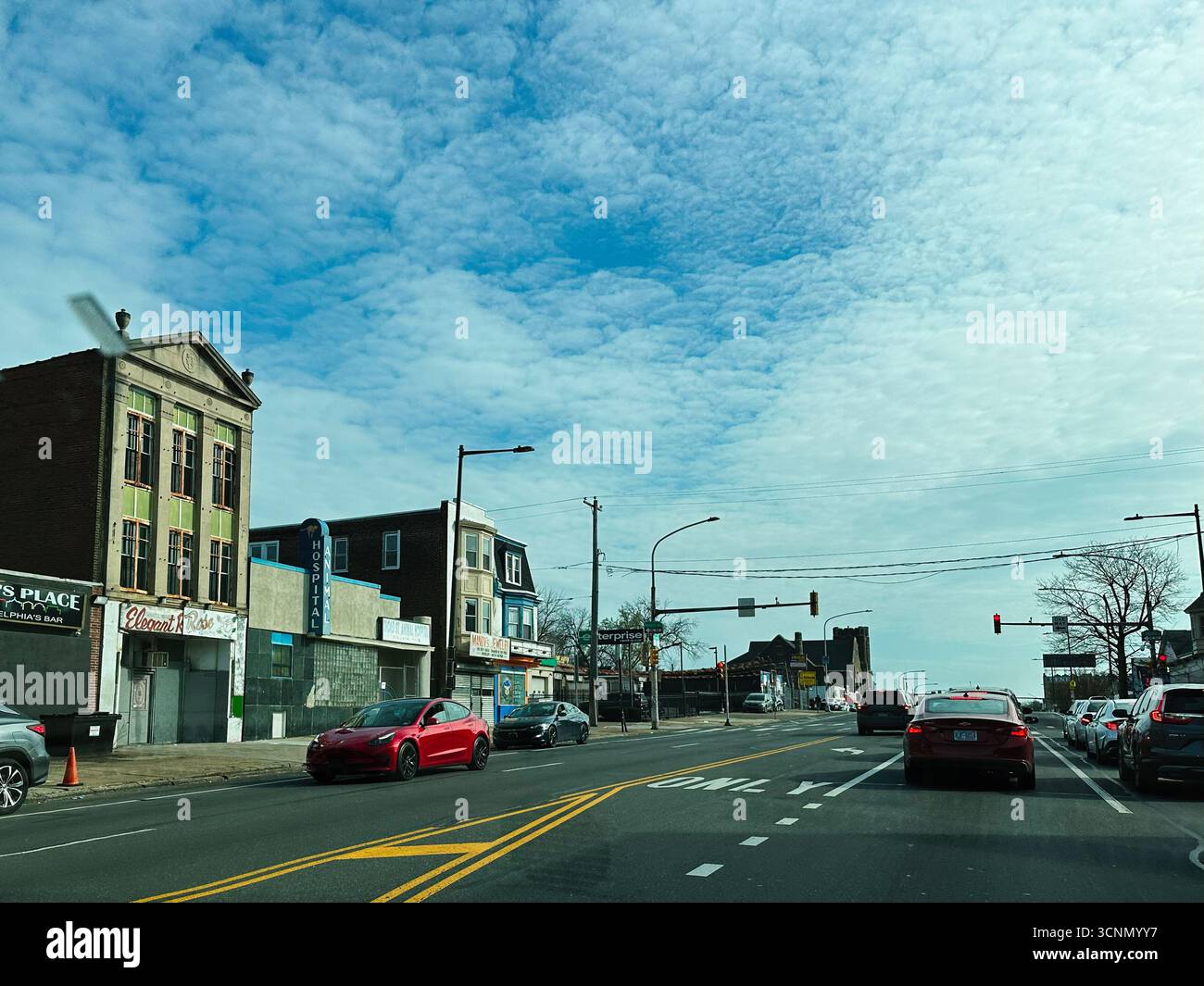 Philadelphia, Pennsylvania, USA - 29. April 2025: Geschäftige urbane Straßenszene in Philadelphia mit Ladenfronten, Verkehr und klarem blauem Himmel. Stockfoto